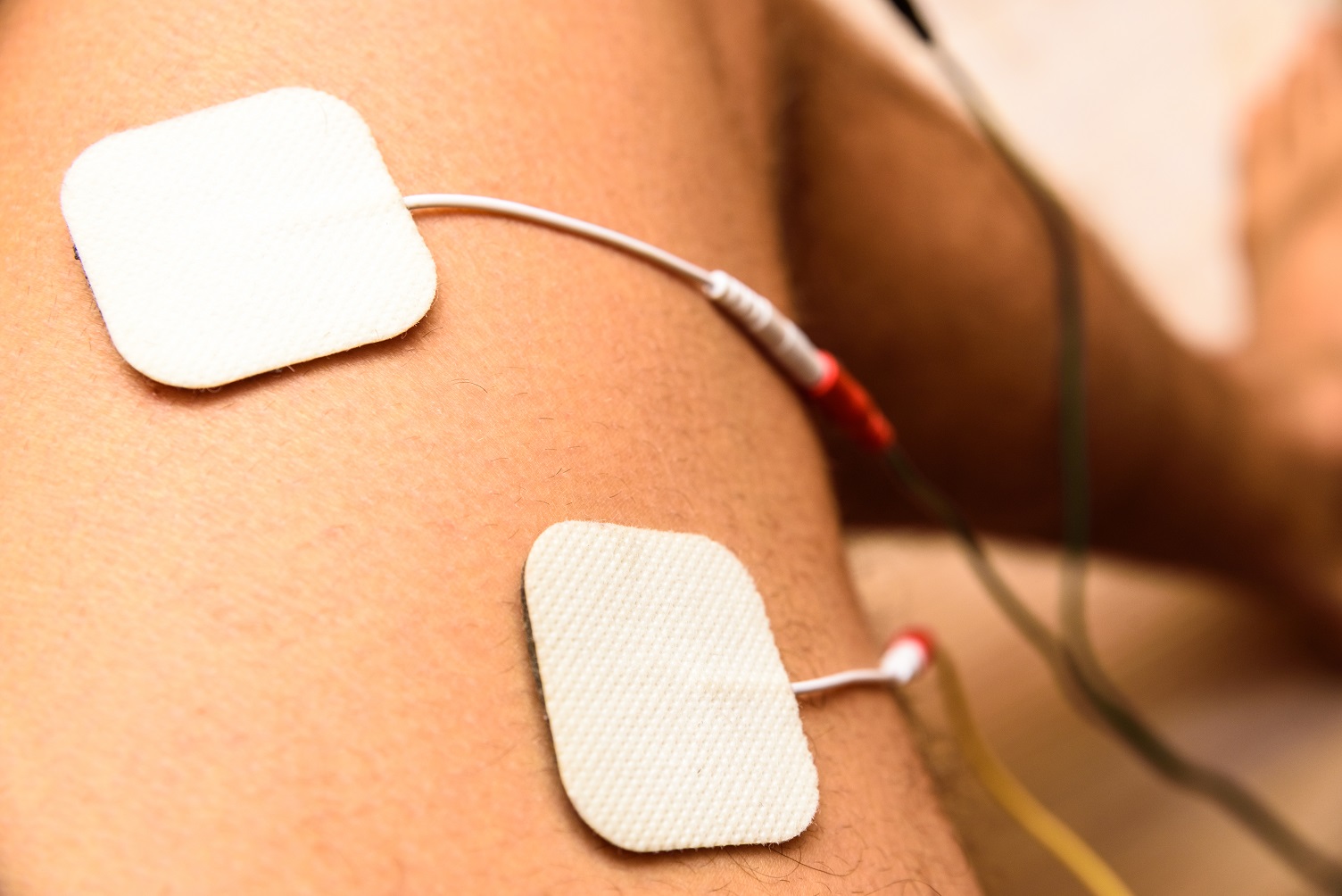 injured athlete applies ems electrodes to his legs