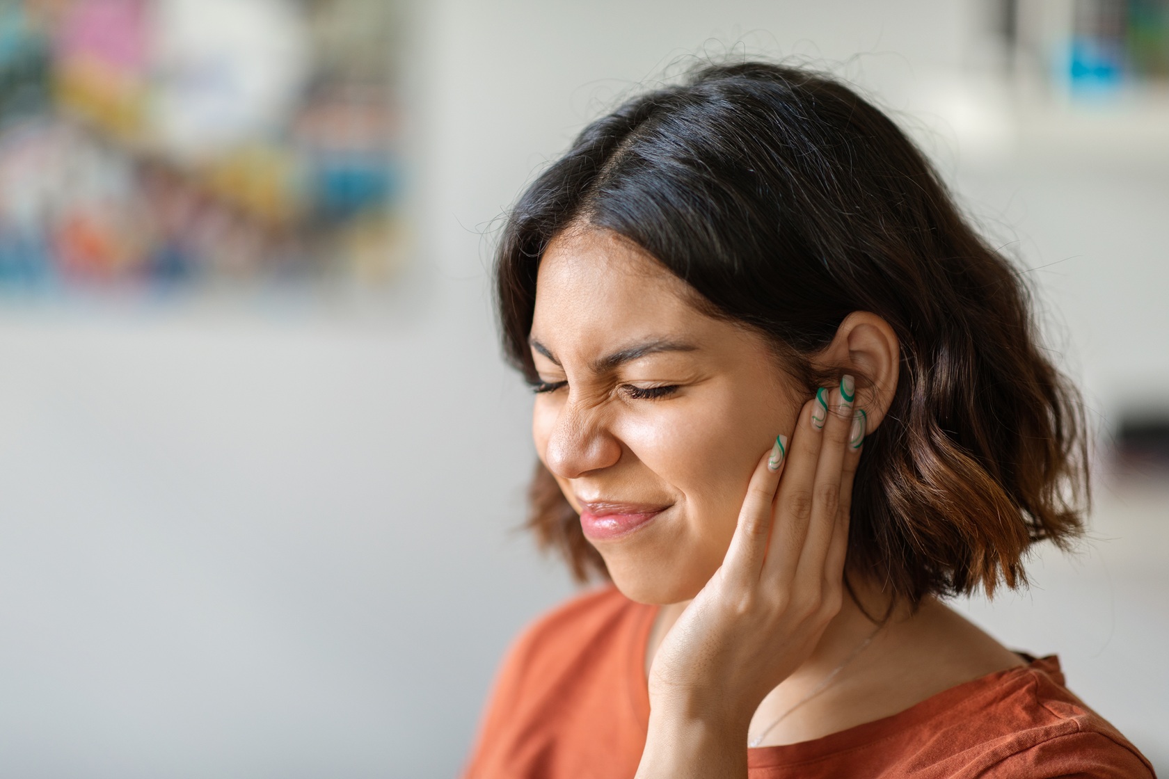 woman experiencing ear pain touching her face 2026