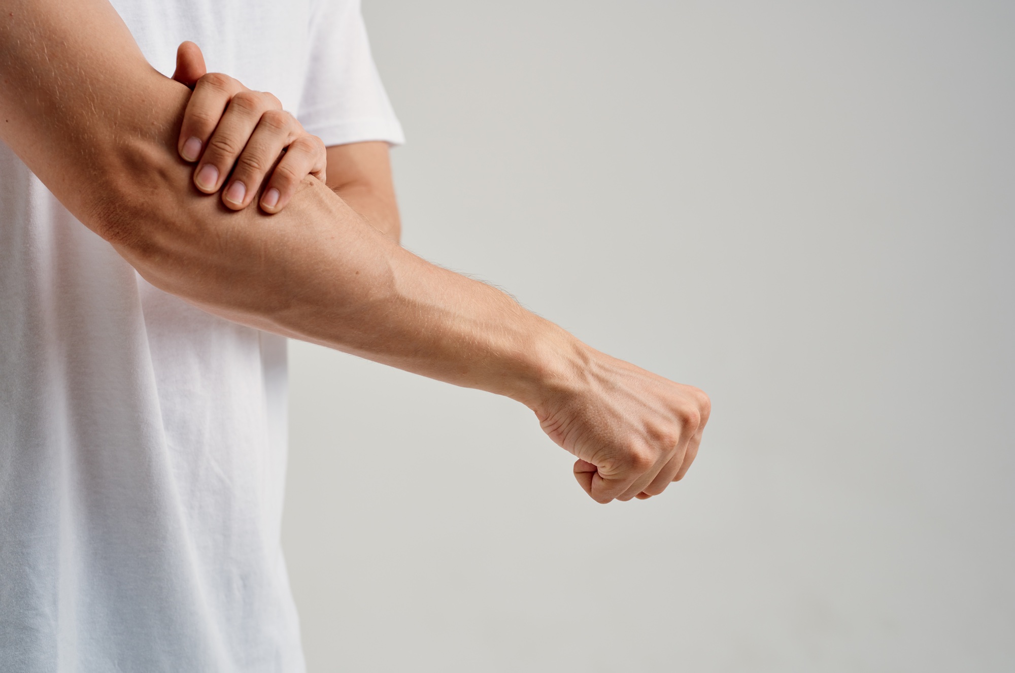 man massaging his aching arm in studio 2026