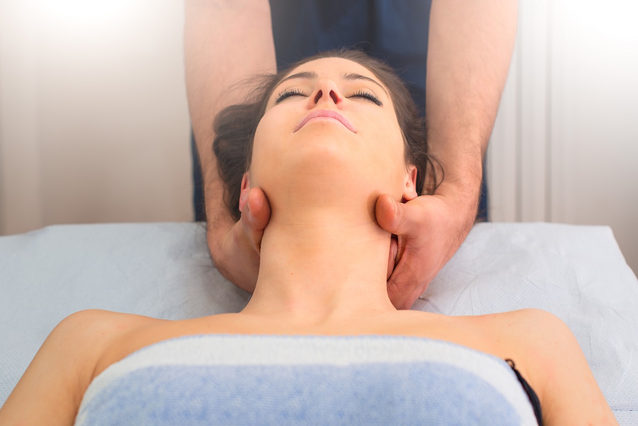 therapist massaging the neck of woman