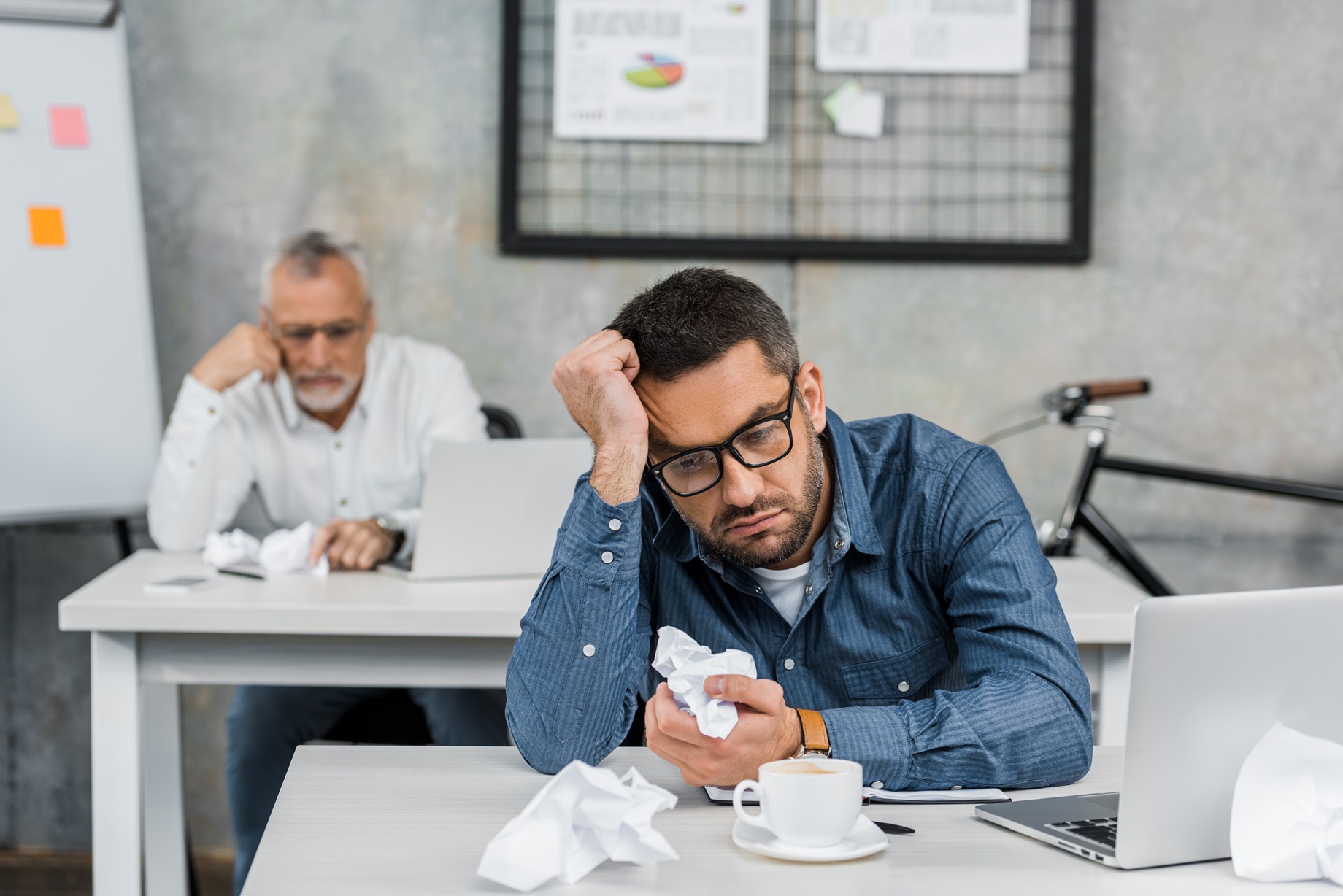 bored buisnessman in eyeglasses holding crumpled 