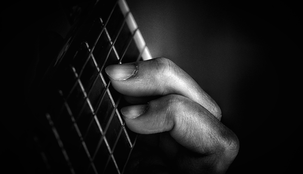 moody close up of guitar strings and hand 2026