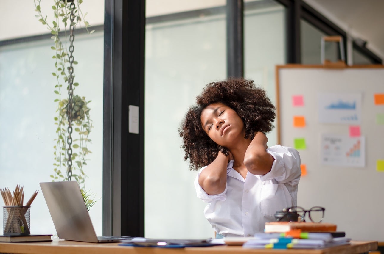 woman massaging neck in office suffering from pain 2026