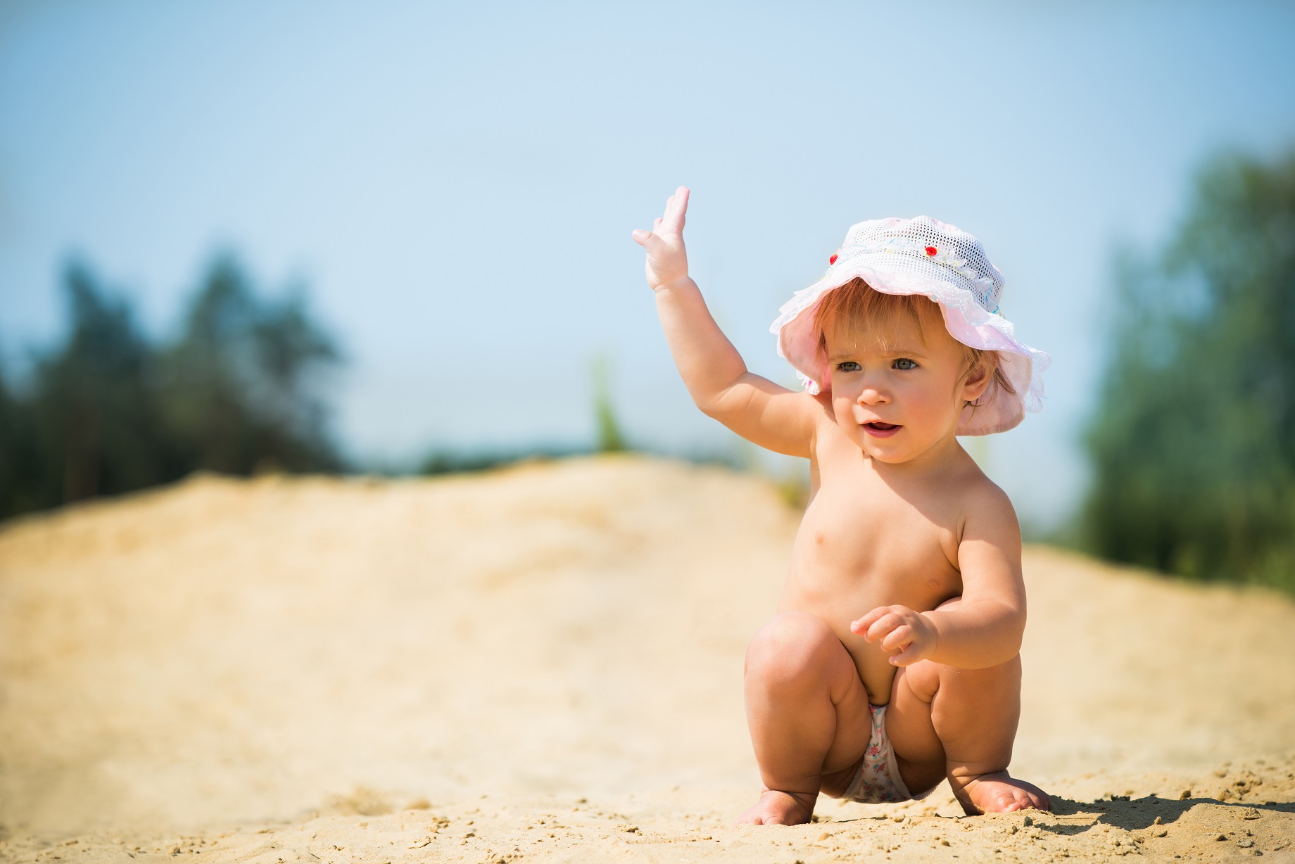 adorable little girl squatting on sand