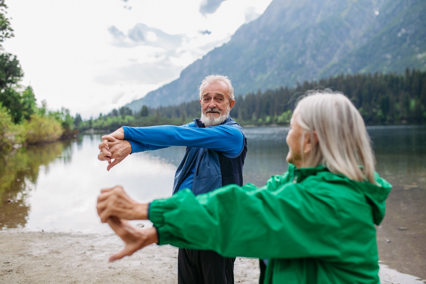 senior couple doing outdoor yoga by the lake