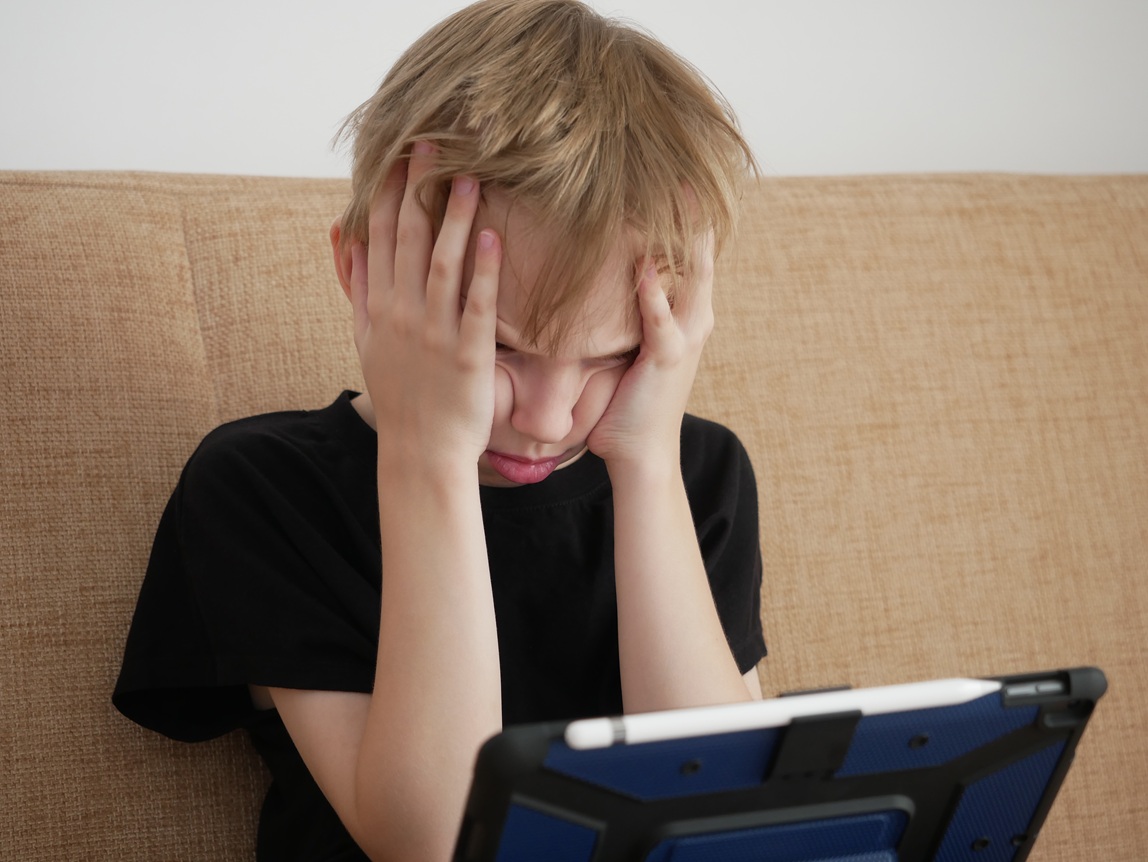 boy gets upset and looks at the tablet 2026